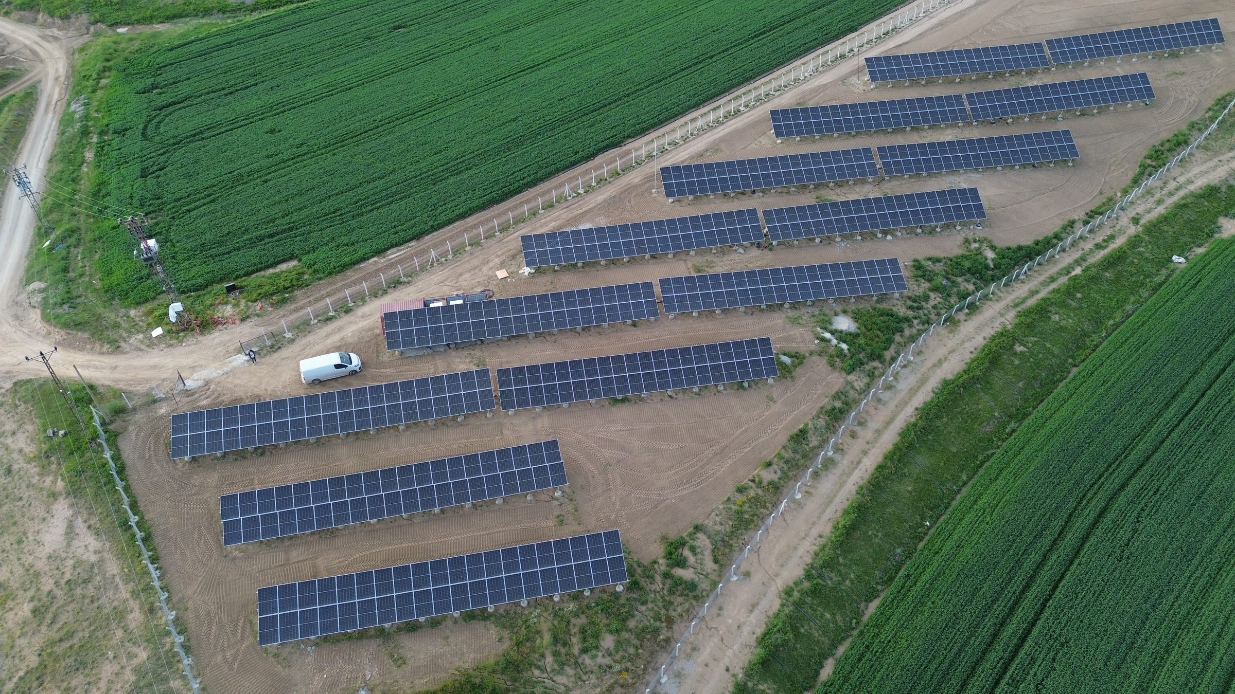 Pandora Enerji tarafından kurulan arazi tipi güneş enerjisi santrali — yeşil tarım arazisinde panel sıraları, drone görünümü